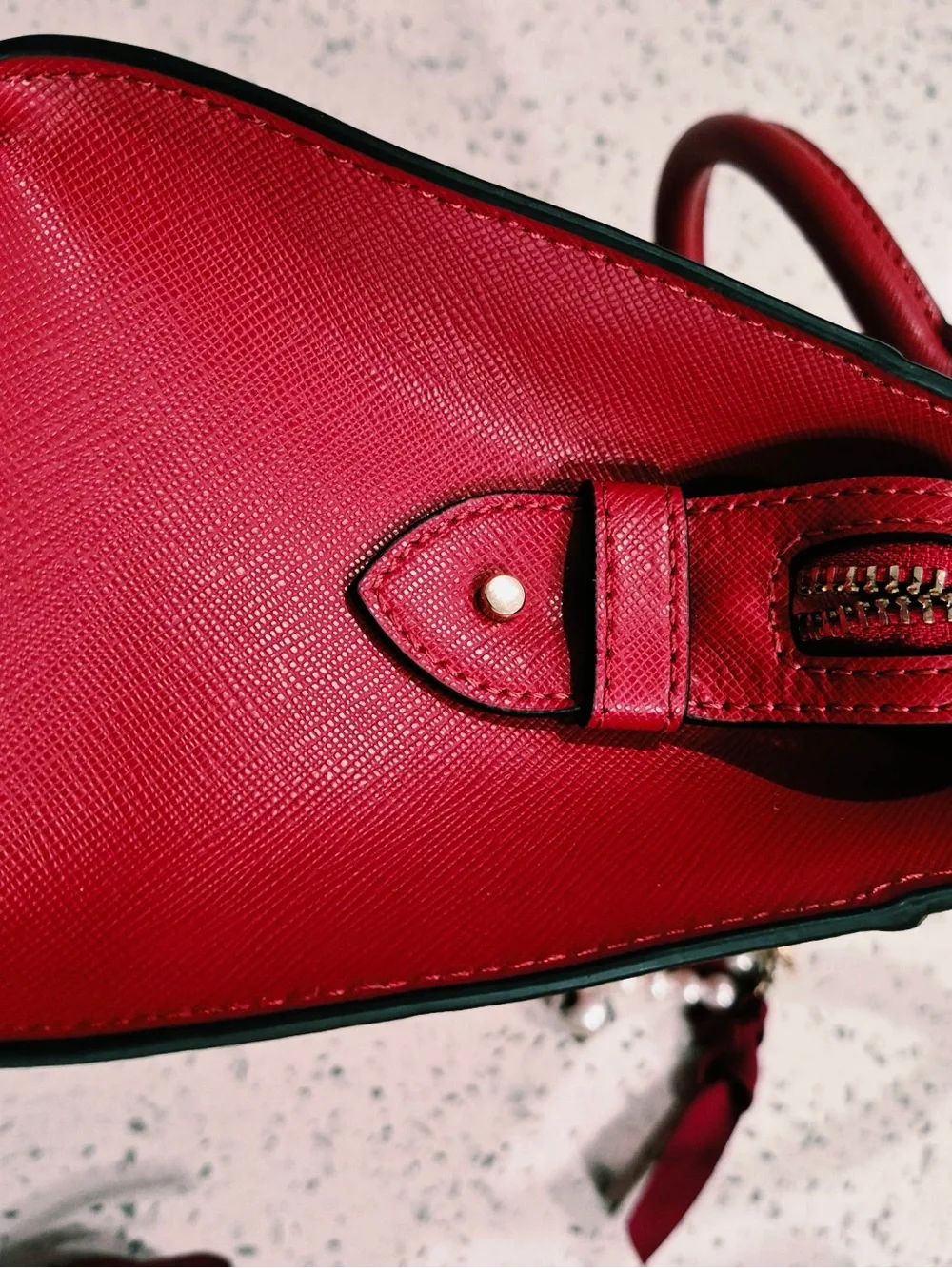 This red satchel is a Kate Spade New York Madison Saffiano Leather